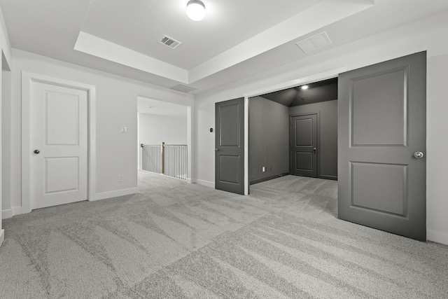 unfurnished bedroom featuring light colored carpet and a raised ceiling