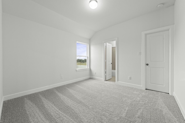 unfurnished bedroom with ensuite bathroom, lofted ceiling, and light carpet