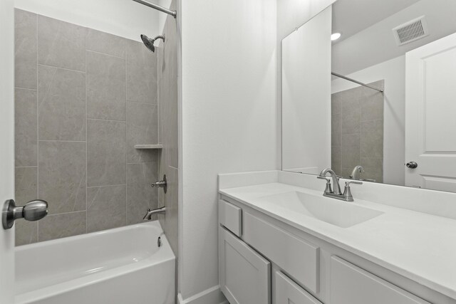 bathroom featuring vanity and tiled shower / bath