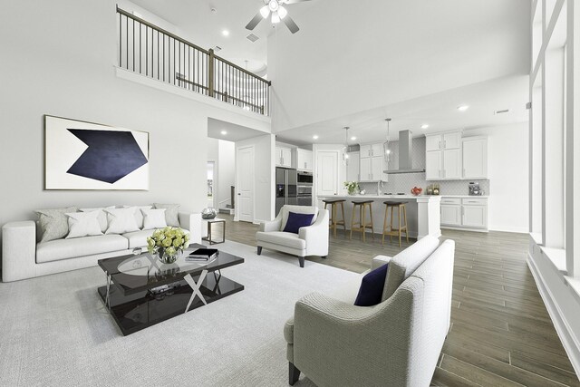 living room featuring ceiling fan, wood-type flooring, and a high ceiling