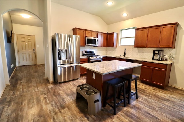 kitchen featuring sink, dark wood-type flooring, stainless steel appliances, vaulted ceiling, and a kitchen island