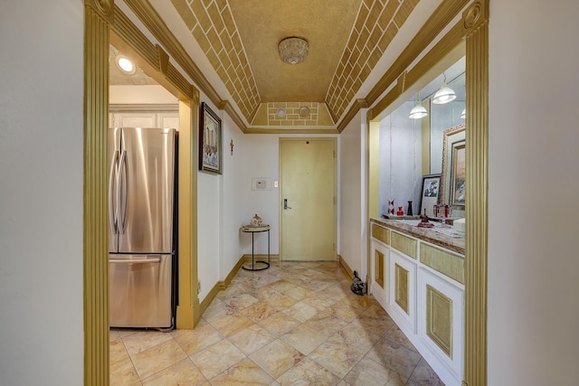 hall featuring a raised ceiling, ornamental molding, and brick ceiling