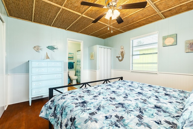 bedroom with wooden ceiling, wooden walls, ceiling fan, connected bathroom, and dark hardwood / wood-style flooring