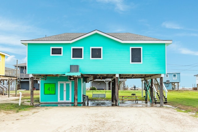 coastal inspired home with cooling unit and a front lawn