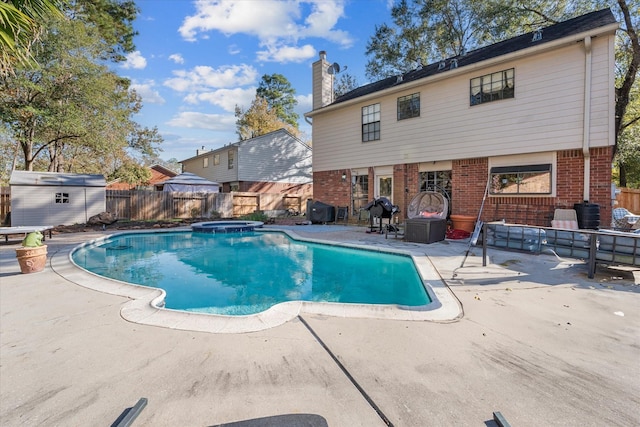 view of swimming pool with an in ground hot tub, a patio, and a shed