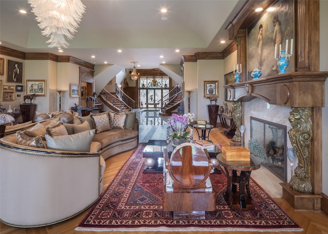 living room with light parquet flooring, a premium fireplace, ornamental molding, and a chandelier