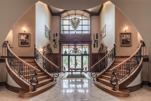 entryway featuring a notable chandelier, a towering ceiling, crown molding, and french doors