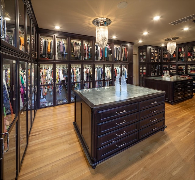 spacious closet with light hardwood / wood-style flooring and a chandelier