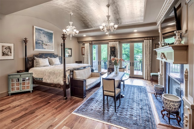 bedroom with french doors, a tray ceiling, access to outside, hardwood / wood-style flooring, and an inviting chandelier