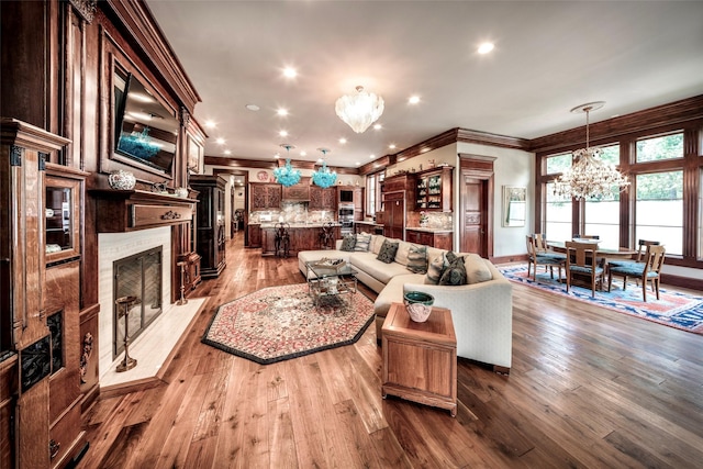 living room with light wood-type flooring, crown molding, and an inviting chandelier