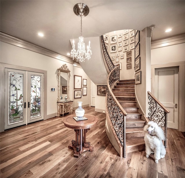 staircase featuring crown molding, french doors, a chandelier, and hardwood / wood-style flooring