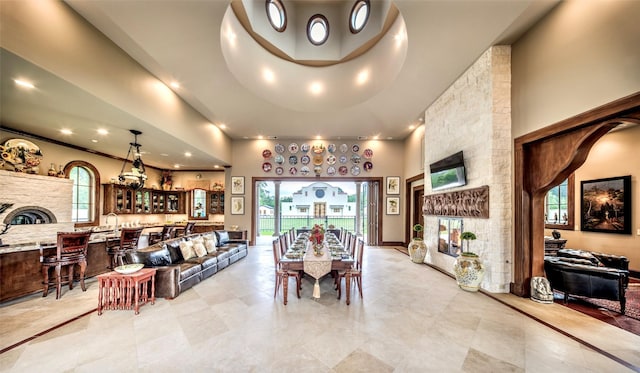 dining area featuring a fireplace, a high ceiling, and bar area