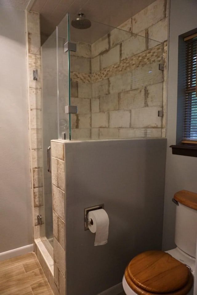 bathroom featuring hardwood / wood-style flooring, toilet, and a shower with shower door