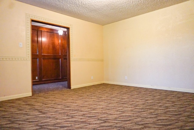 unfurnished room with dark carpet and a textured ceiling