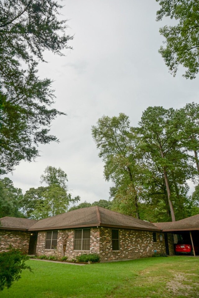 view of side of property with a carport and a lawn