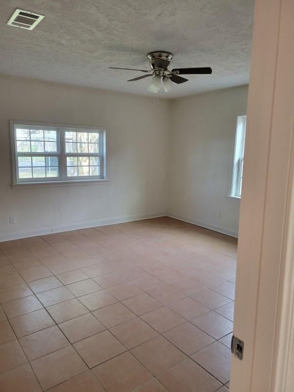 spare room featuring light tile patterned floors, a textured ceiling, and ceiling fan