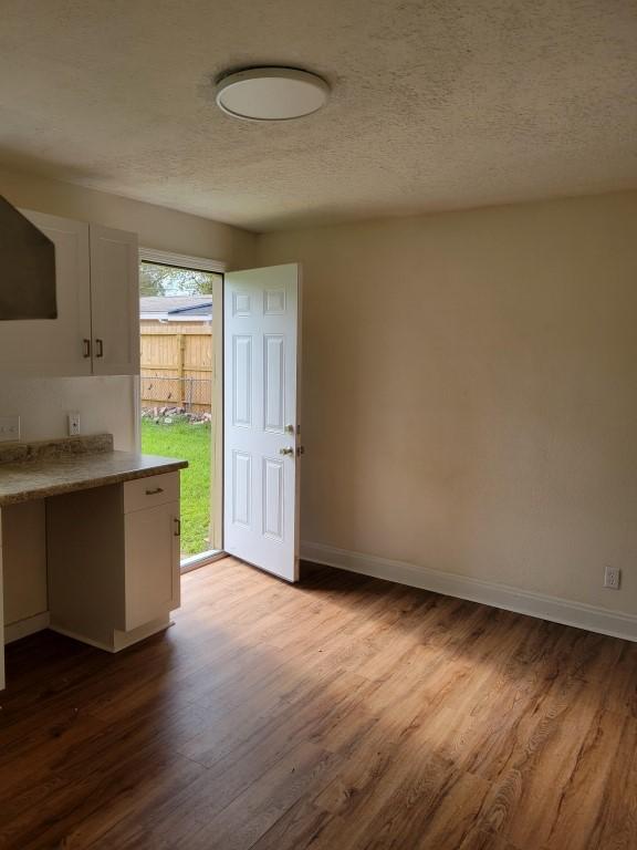 interior space with range hood, white cabinetry, light hardwood / wood-style flooring, and a textured ceiling