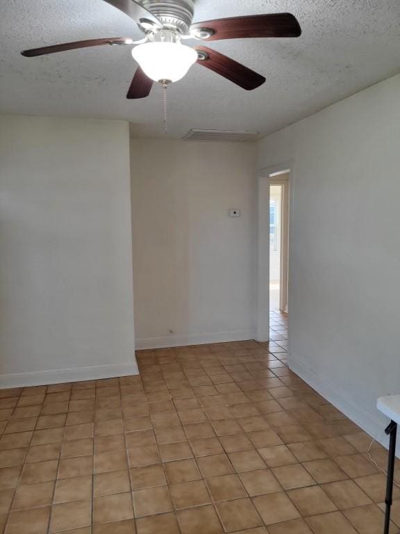 tiled empty room featuring ceiling fan and a textured ceiling