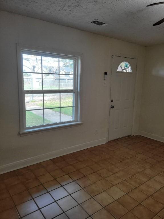 entrance foyer featuring ceiling fan, light tile patterned floors, and a textured ceiling