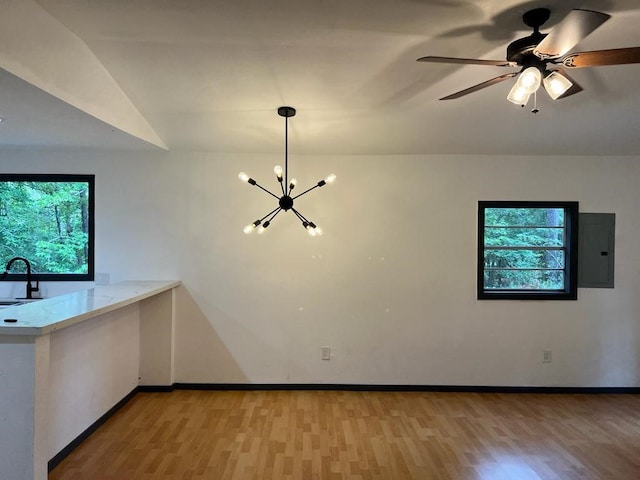 unfurnished living room featuring ceiling fan with notable chandelier, electric panel, light hardwood / wood-style floors, and sink