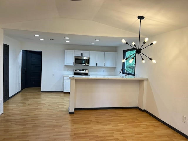 kitchen with light hardwood / wood-style floors, white cabinetry, stainless steel appliances, and an inviting chandelier