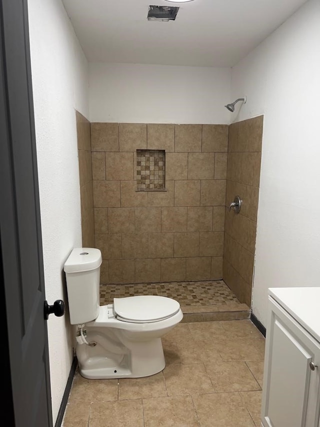 bathroom with tiled shower, vanity, toilet, and tile patterned flooring