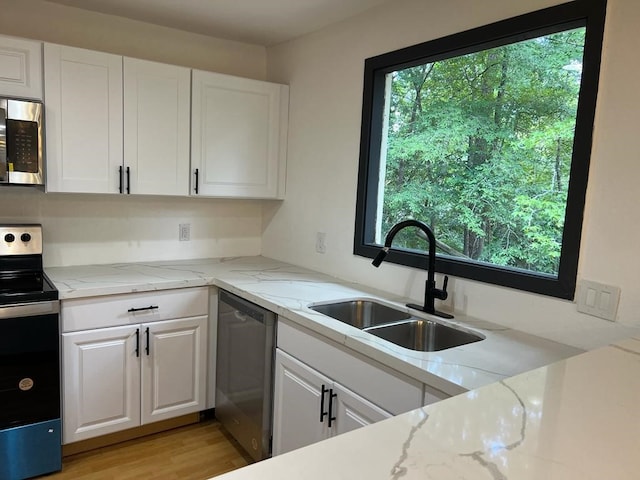 kitchen with sink, stainless steel appliances, light stone counters, light hardwood / wood-style flooring, and white cabinets