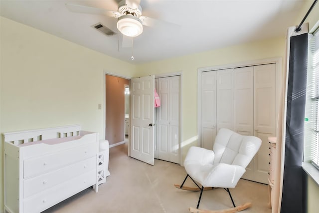 carpeted bedroom featuring ceiling fan and two closets