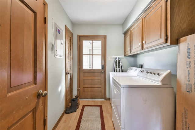 clothes washing area with independent washer and dryer, cabinets, electric panel, and light hardwood / wood-style floors