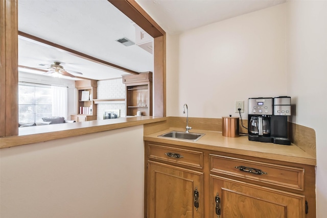 kitchen with a brick fireplace, sink, ceiling fan, and kitchen peninsula