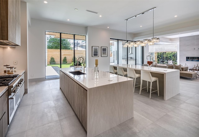 kitchen with a spacious island, sink, pendant lighting, a breakfast bar, and range with two ovens