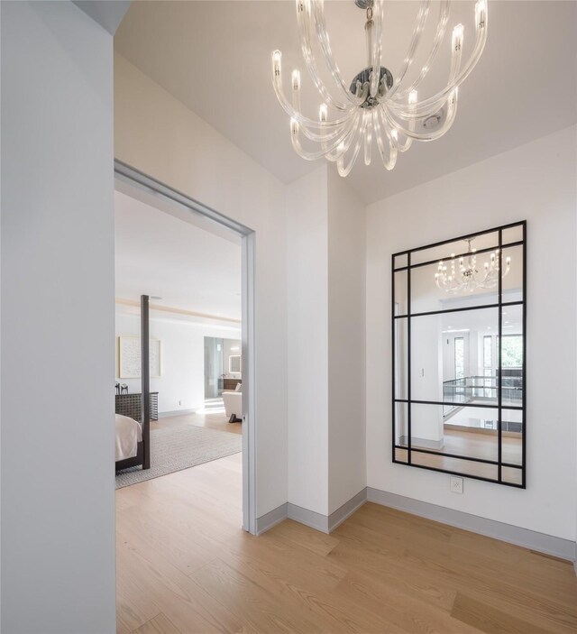 spare room featuring light wood-type flooring and a notable chandelier