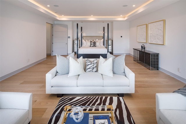 bedroom with light hardwood / wood-style floors and a tray ceiling