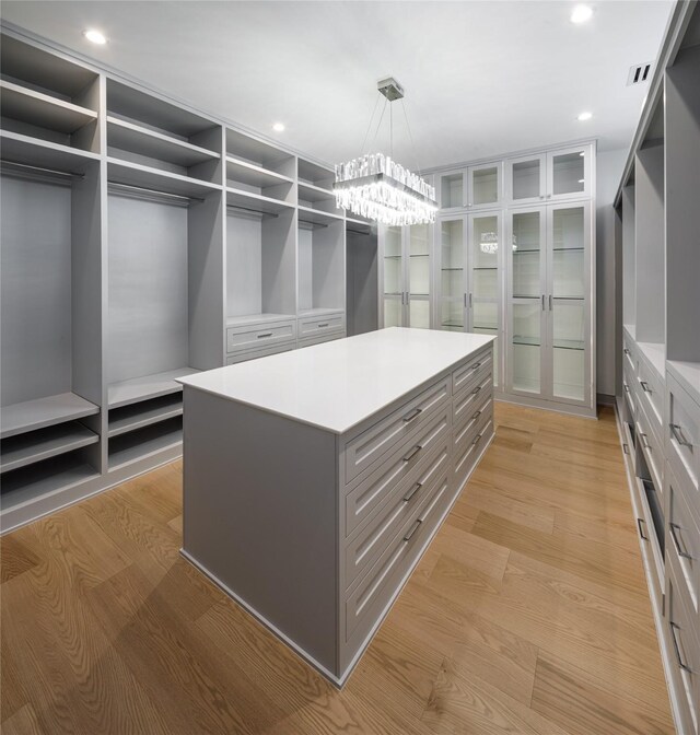 walk in closet with a chandelier and light hardwood / wood-style floors