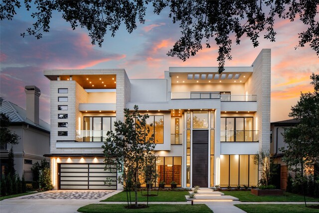 contemporary home featuring a balcony, a garage, and a lawn