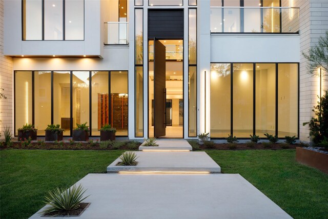 view of exterior entry featuring a balcony and a yard