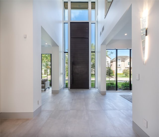 entryway featuring a wall of windows, visible vents, a towering ceiling, and baseboards