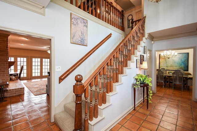 stairway featuring crown molding, ceiling fan with notable chandelier, and a towering ceiling