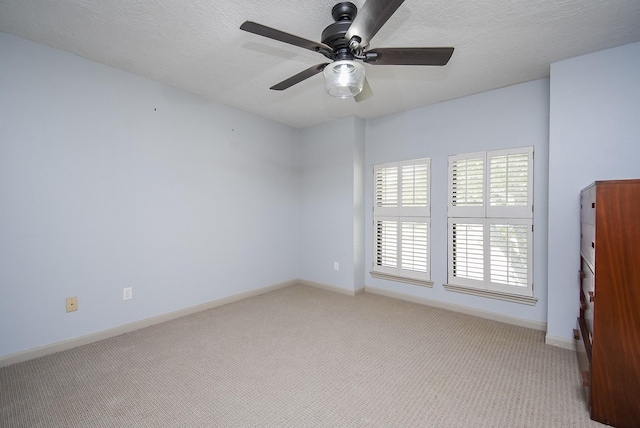 empty room featuring ceiling fan, light colored carpet, and a textured ceiling