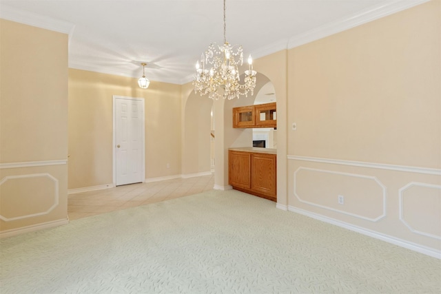 empty room featuring light colored carpet, ornamental molding, and an inviting chandelier