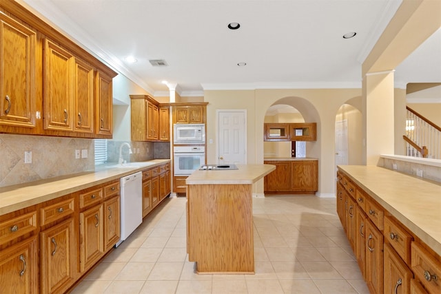 kitchen featuring tasteful backsplash, ornamental molding, white appliances, light tile patterned floors, and a center island