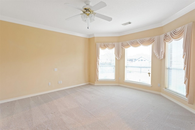 carpeted empty room with a wealth of natural light, ornamental molding, and ceiling fan