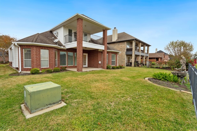 back of house with a lawn, a patio area, and a balcony