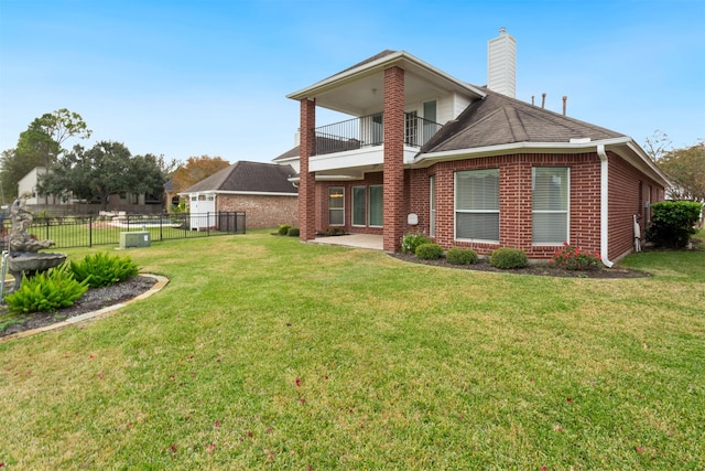 back of property with a lawn and a balcony