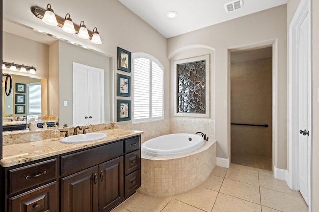 bathroom with vanity, a relaxing tiled tub, and tile patterned floors