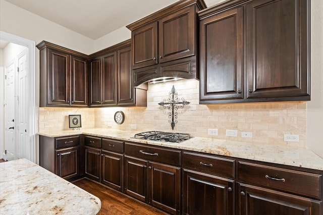 kitchen featuring decorative backsplash, light stone countertops, dark hardwood / wood-style floors, and stainless steel gas cooktop