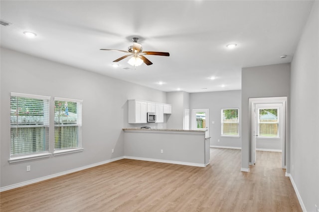 unfurnished living room featuring ceiling fan and light wood-type flooring