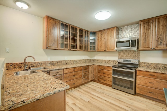 kitchen featuring sink, light hardwood / wood-style floors, light stone countertops, and appliances with stainless steel finishes