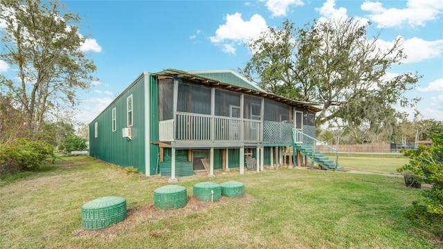 rear view of house featuring a yard and a sunroom