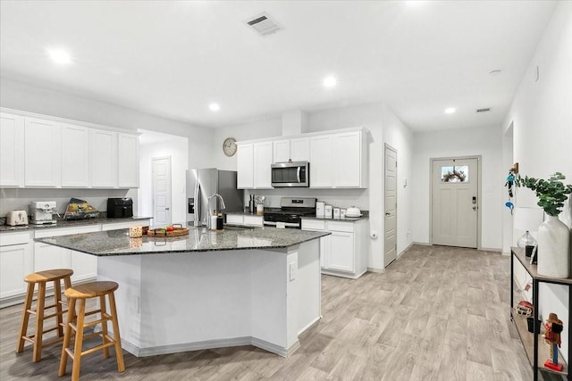 kitchen with a kitchen island with sink, white cabinets, sink, light hardwood / wood-style flooring, and stainless steel appliances